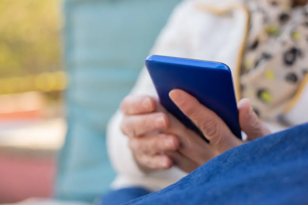 Person on a sofa holding a phone in a bright blue case